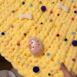 Yellow textured blanket with colorful polka dots held by a hand